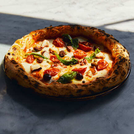 Neapolitanische Pizza mit Datteltomaten, Oliven und Basilikum