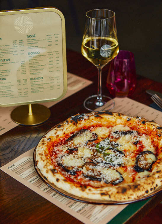 Pizza mit Auberginen und Parmesan, dazu ein Glas Weißwein